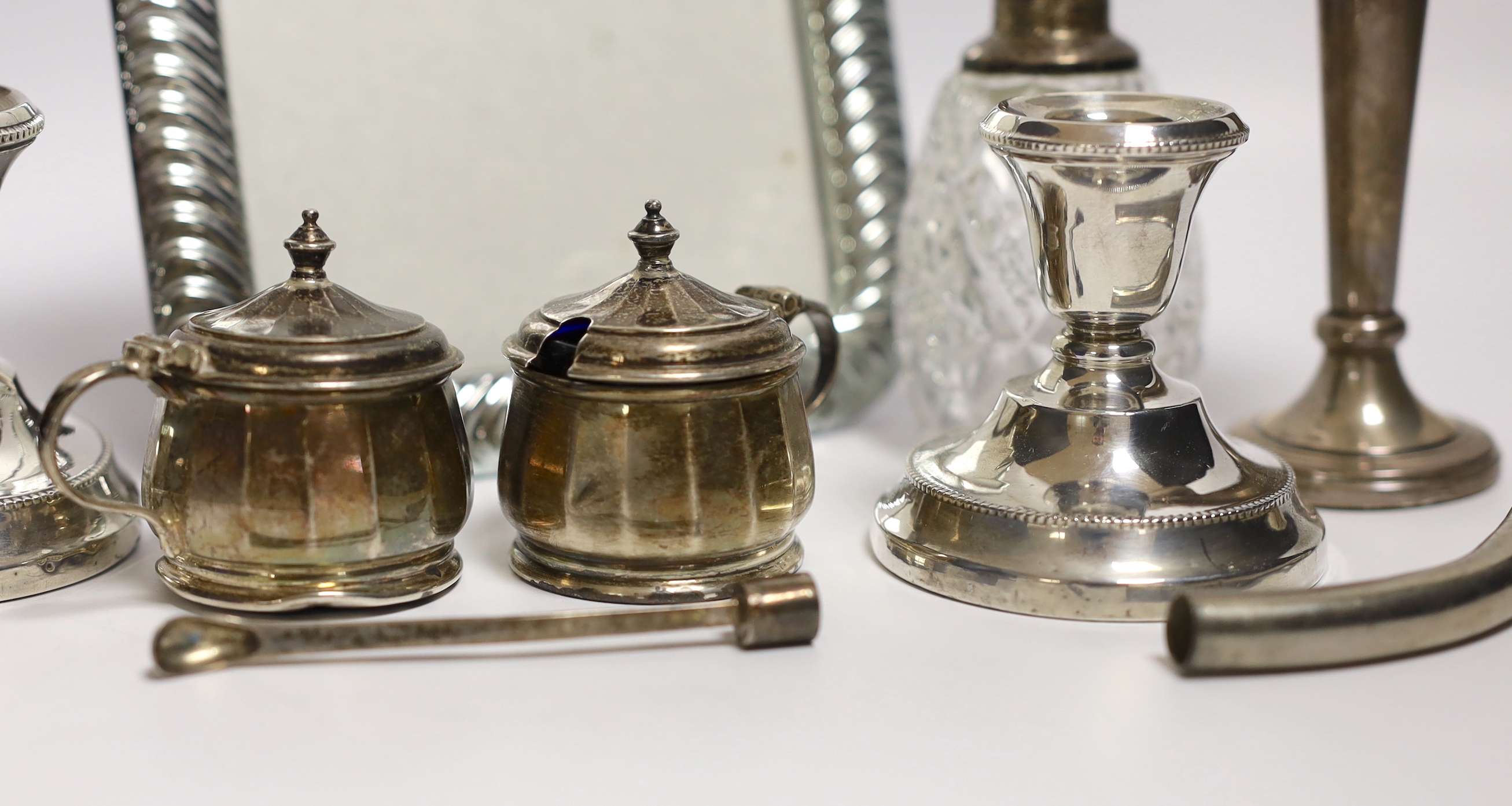 Sundry small silver including a pair of dwarf candlesticks, condiments, napkin ring, spill vases and a modern 925 mounted photograph frame.